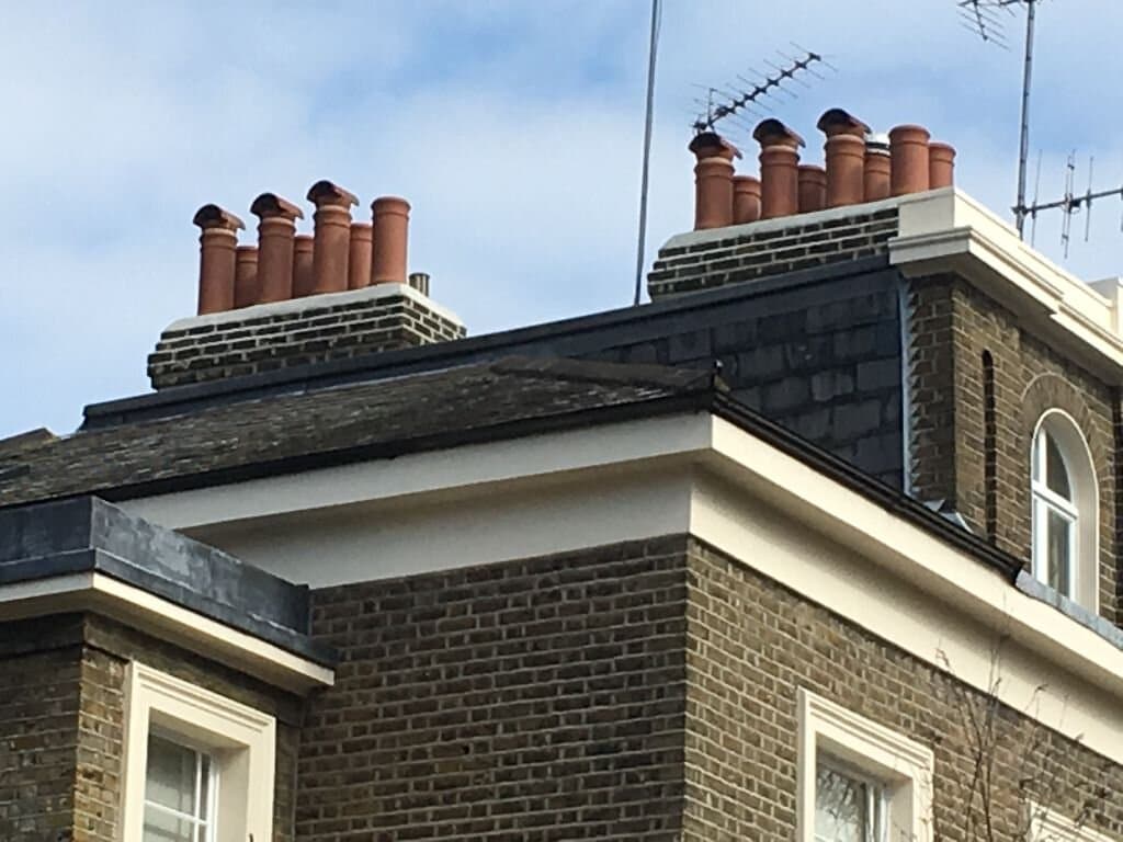Chimney and roofline repair viewed across neighboring homes