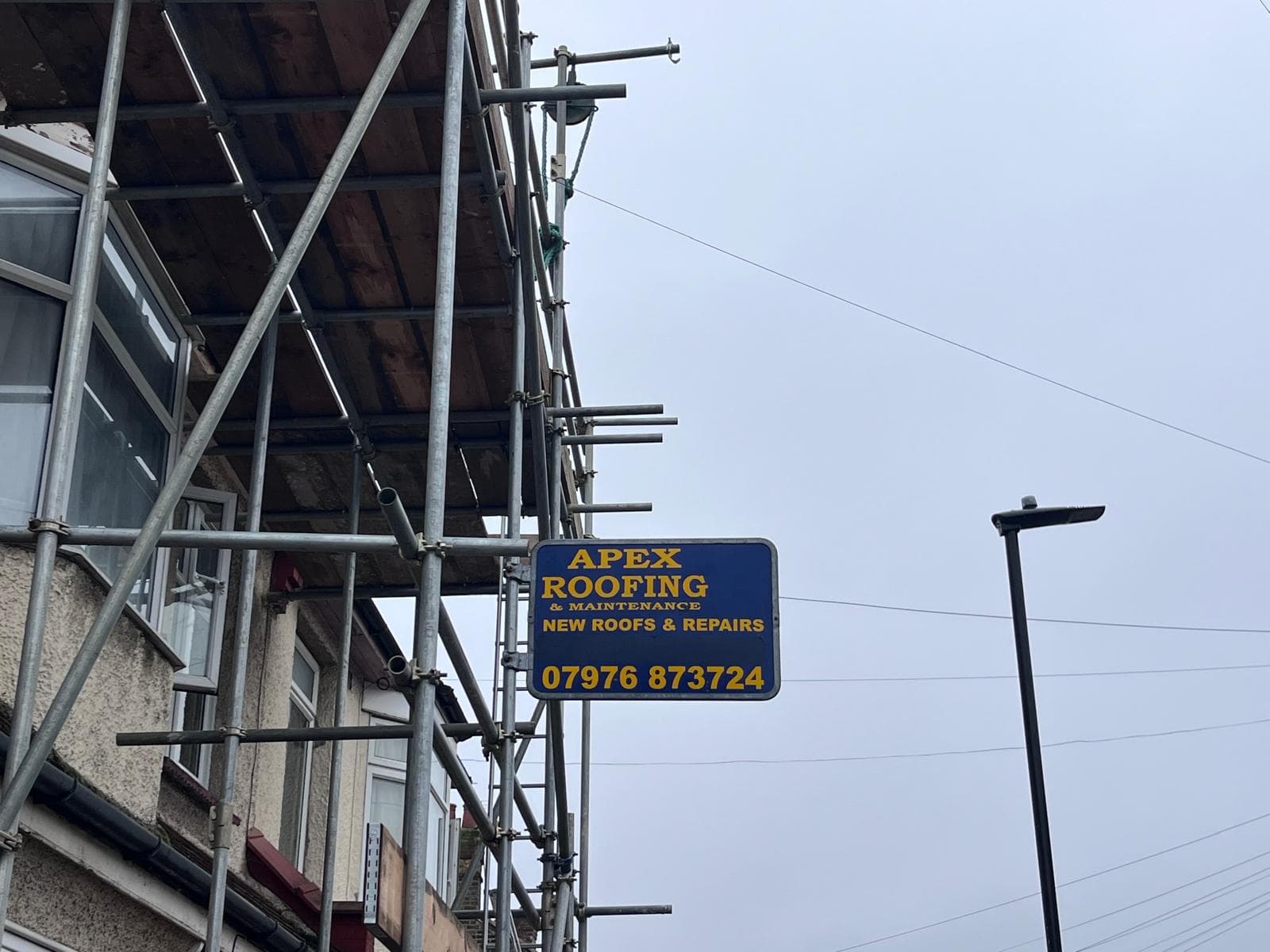 Apex Roofing sign photographed at a completed project site